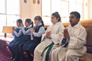 Students and alter servers in prayer at church